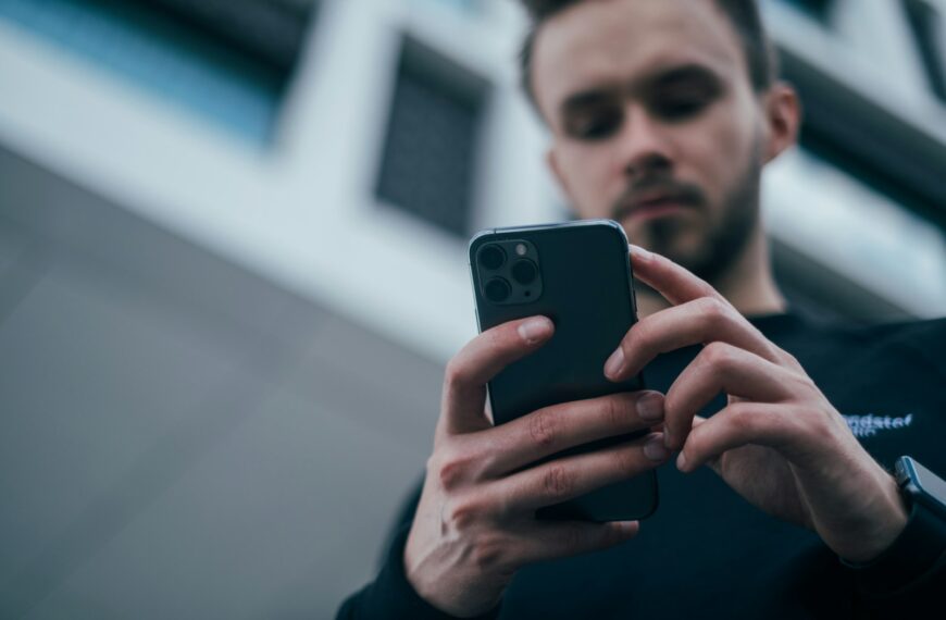 man wearing black sweater using smartphone