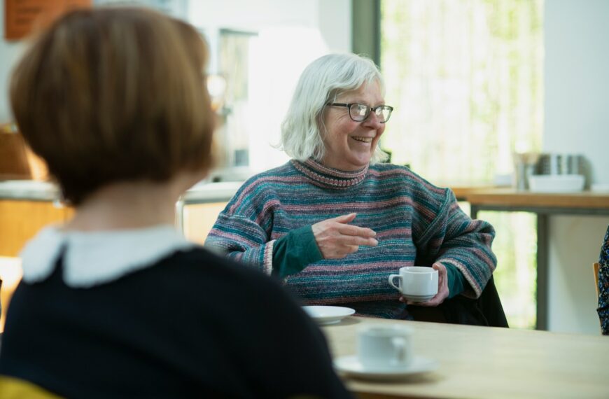 a woman sitting at a table talking to another woman