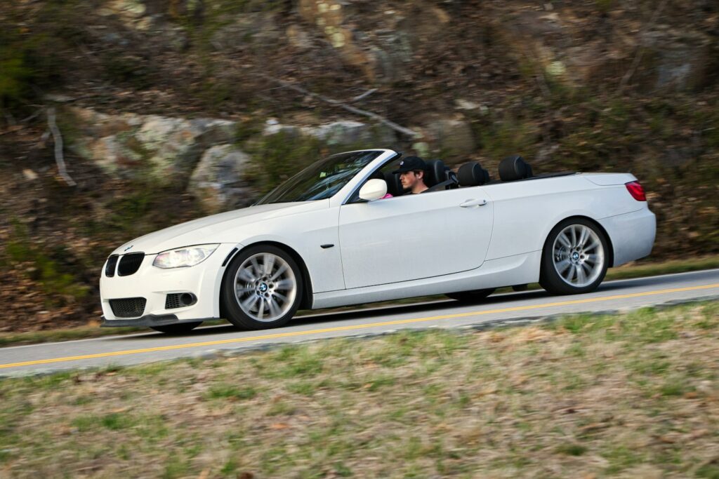 White convertible driving on a winding road.
