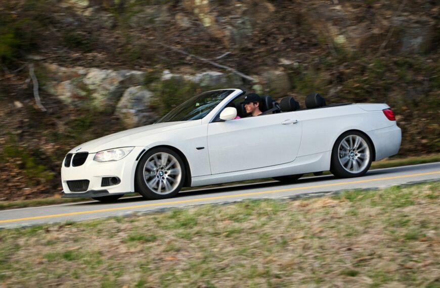 White convertible driving on a winding road.