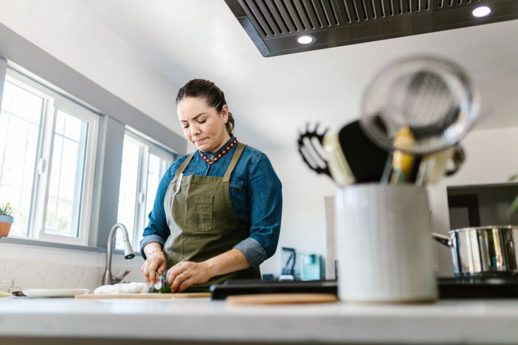 A woman in a domestic kitchen focused on chopping vegetables, creating a warm culinary atmosphere.