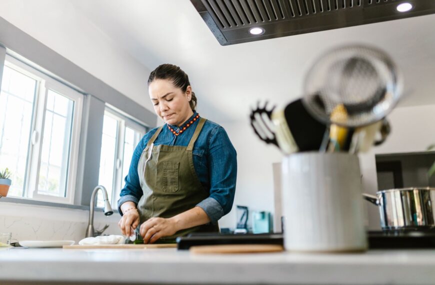 A woman in a domestic kitchen focused on chopping vegetables, creating a warm culinary atmosphere.
