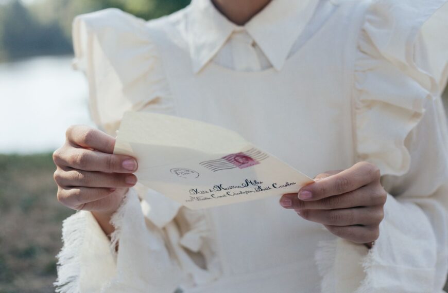 A woman in a white dress holds an old-fashioned love letter with serene background.