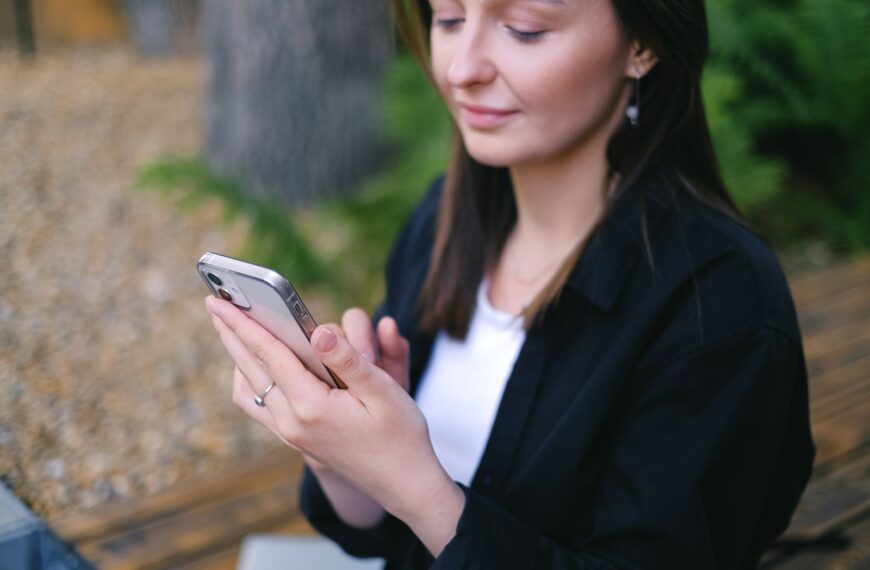Woman using smartphone outdoors, embracing leisure and relaxation.