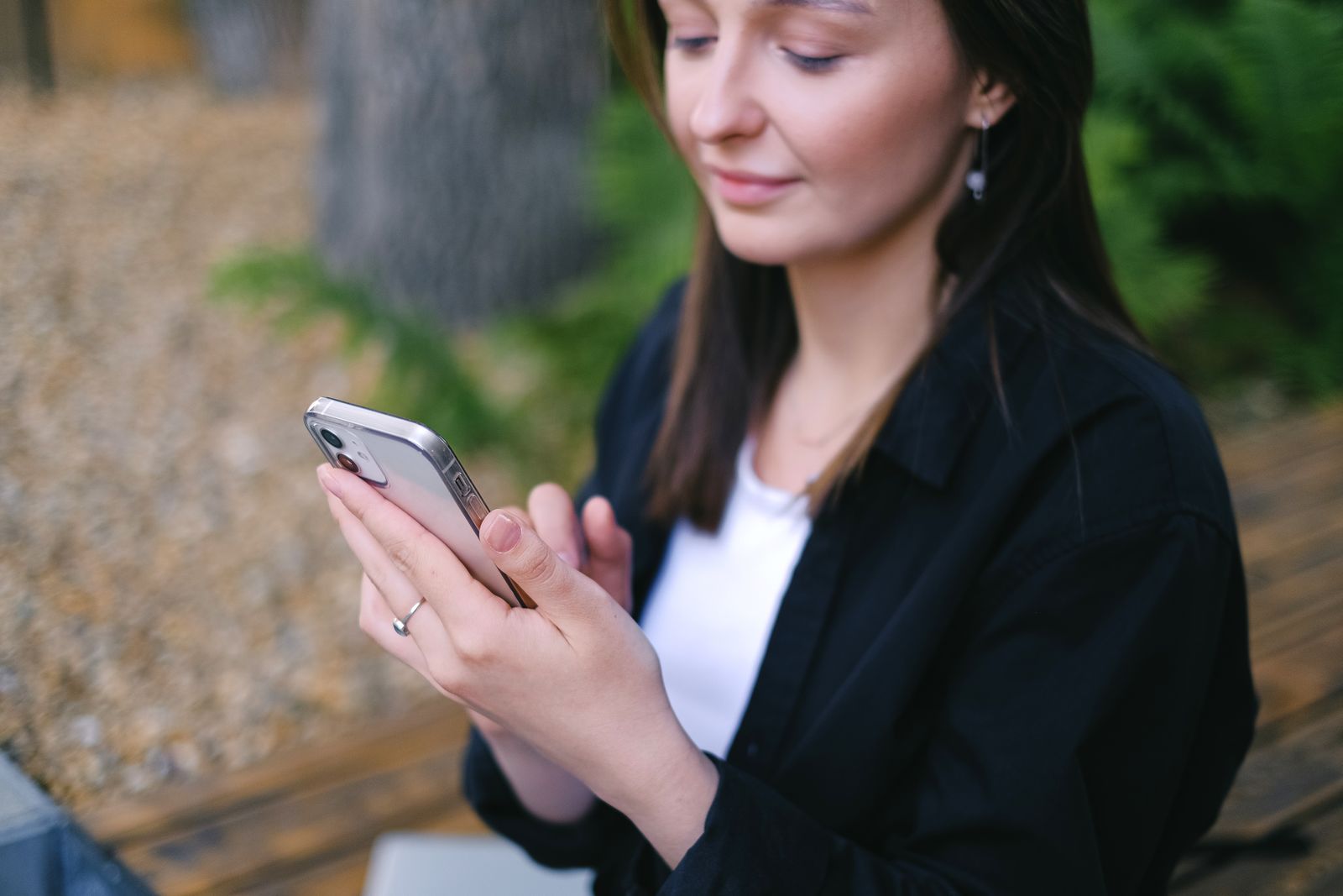 Woman using smartphone outdoors, embracing leisure and relaxation.