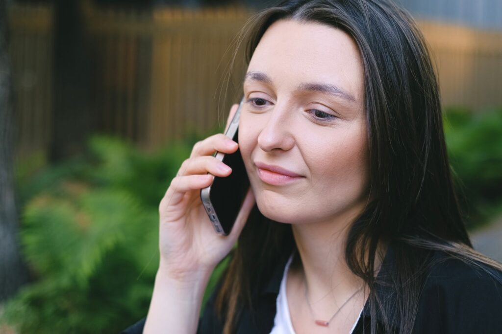 A young woman having a phone conversation in a serene outdoor setting, showcasing digital nomad lifestyle.