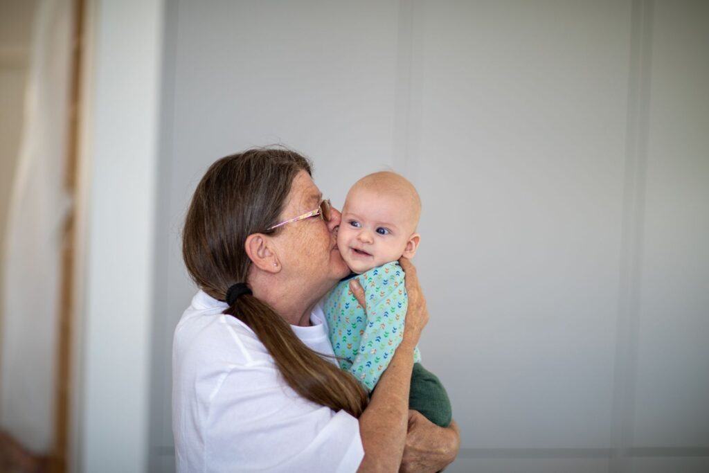 A joyful moment between a loving grandmother and her smiling grandchild indoors.