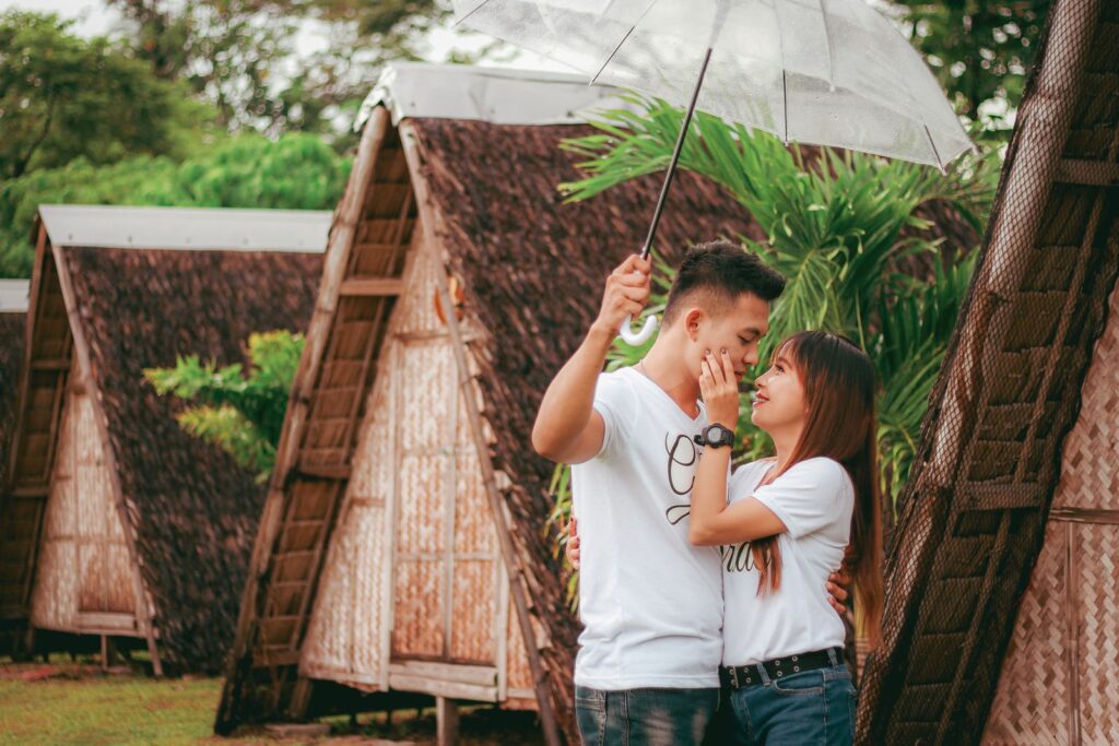 Young couple sharing an intimate moment under an umbrella outdoors.