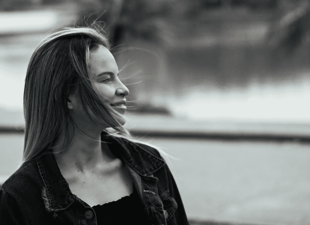 Captivating black and white portrait of a smiling woman in a denim jacket outdoors.