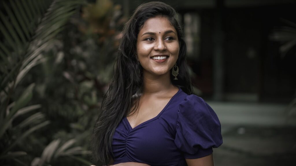 Cheerful Indian woman smiling outdoors, showcasing traditional beauty and happiness.