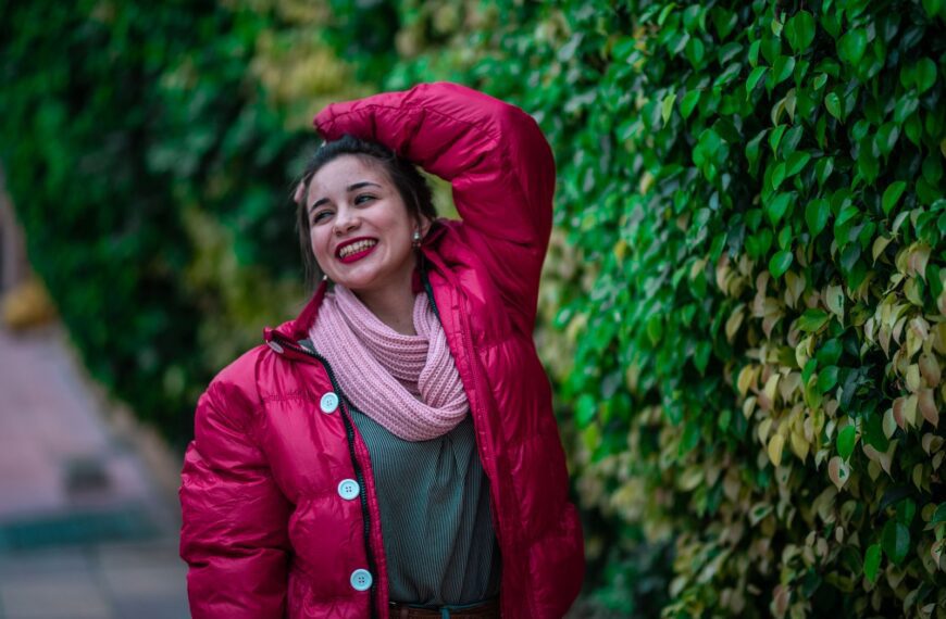 Cheerful woman in a pink winter jacket expressing joy outdoors.
