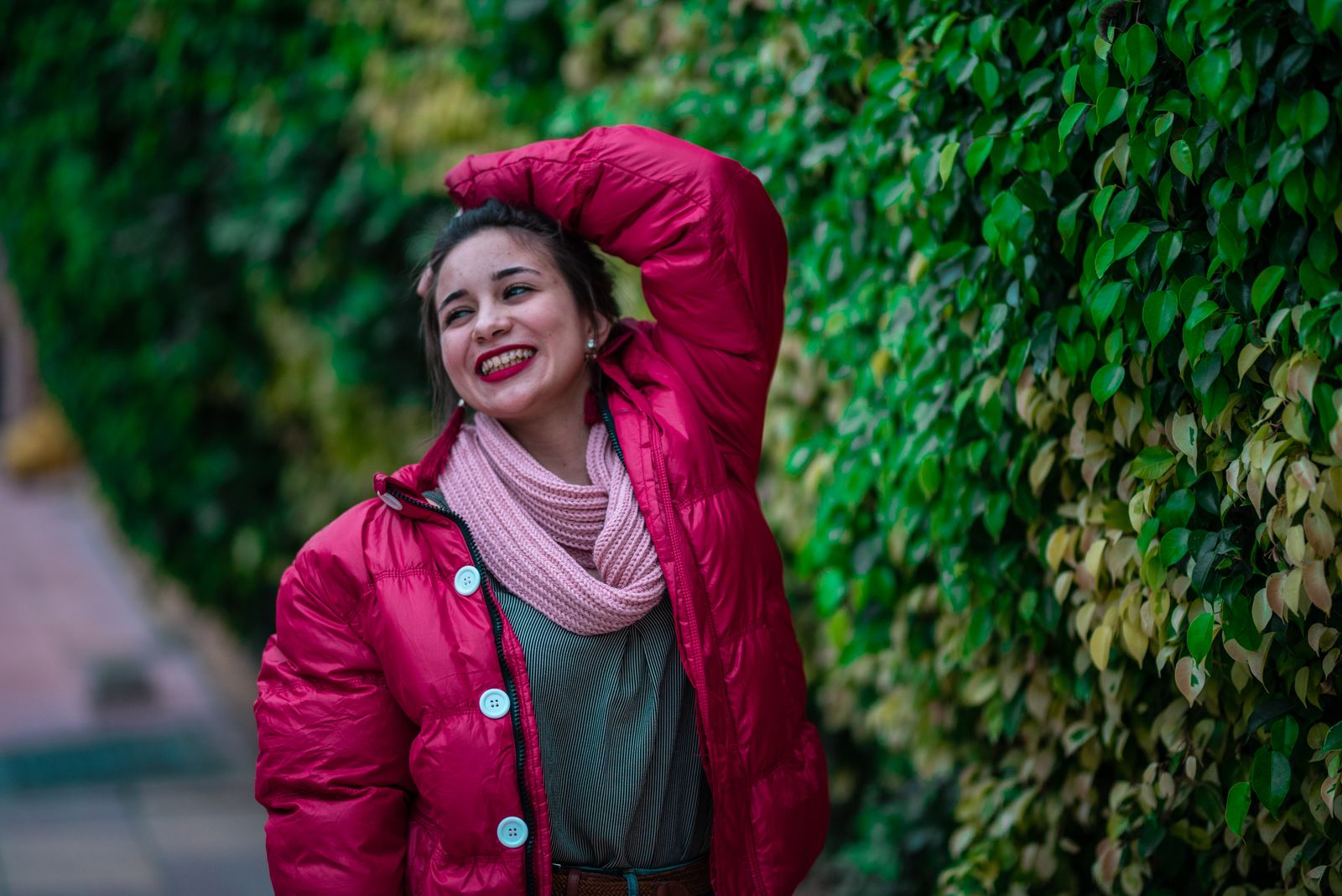 Cheerful woman in a pink winter jacket expressing joy outdoors.