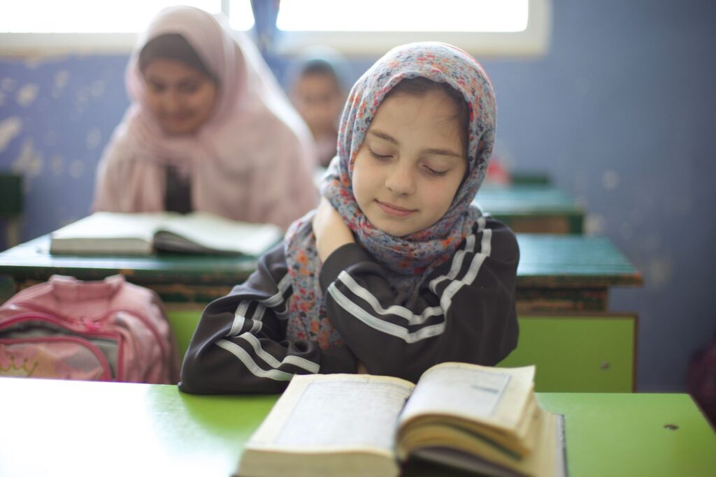 Young schoolgirls in Jordanian classroom studying attentively. Promotes education and cultural diversity.