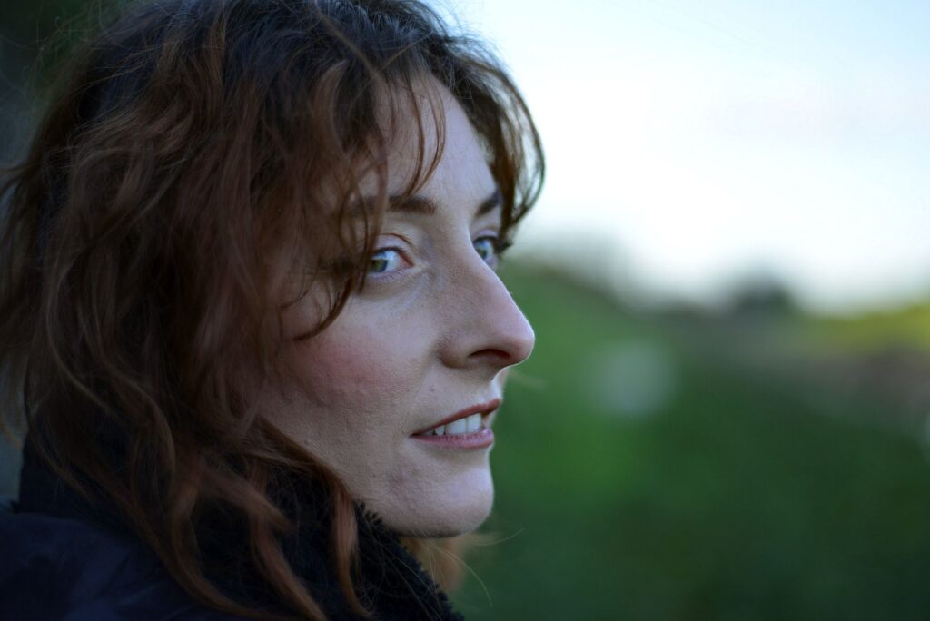 Close-up portrait of a woman outdoors with a thoughtful expression, focusing on natural beauty.
