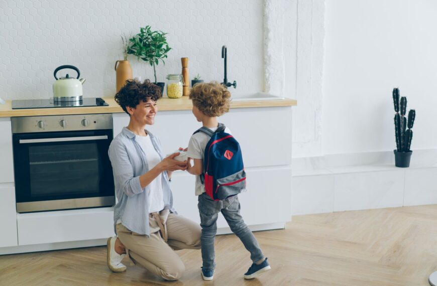 Mother shares a loving moment with her son before school in a modern kitchen.