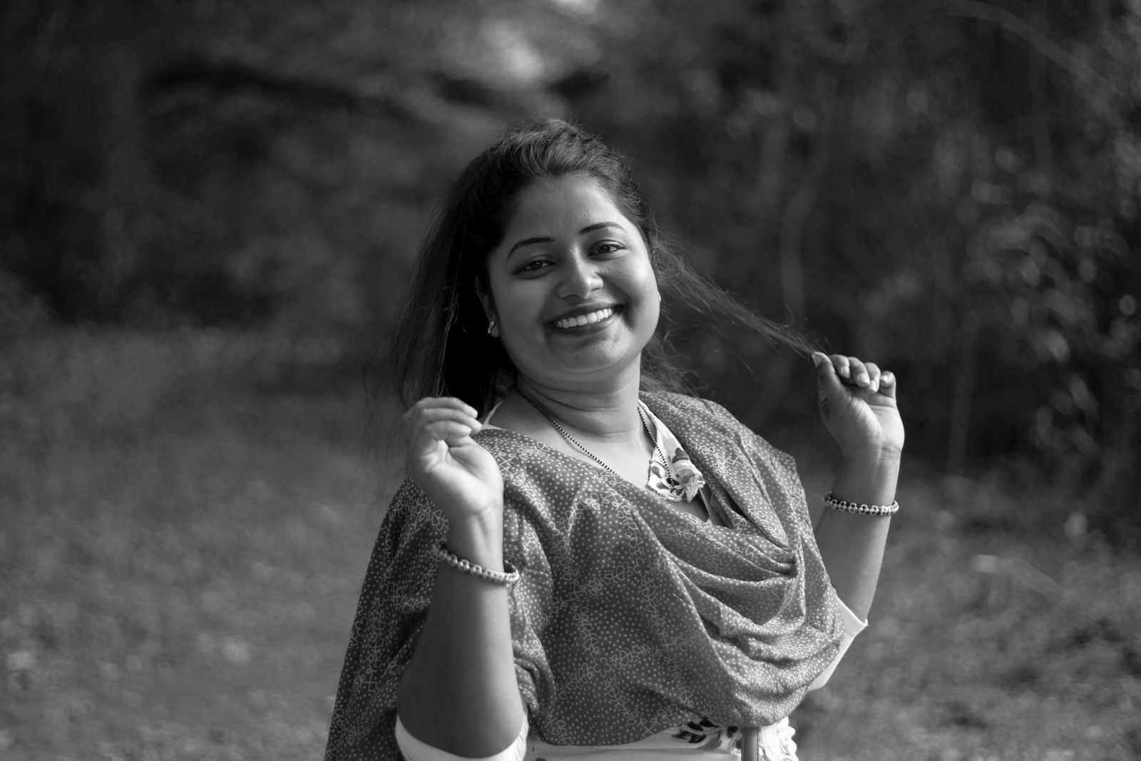 A joyful woman in traditional dress smiling in a rural outdoor setting.
