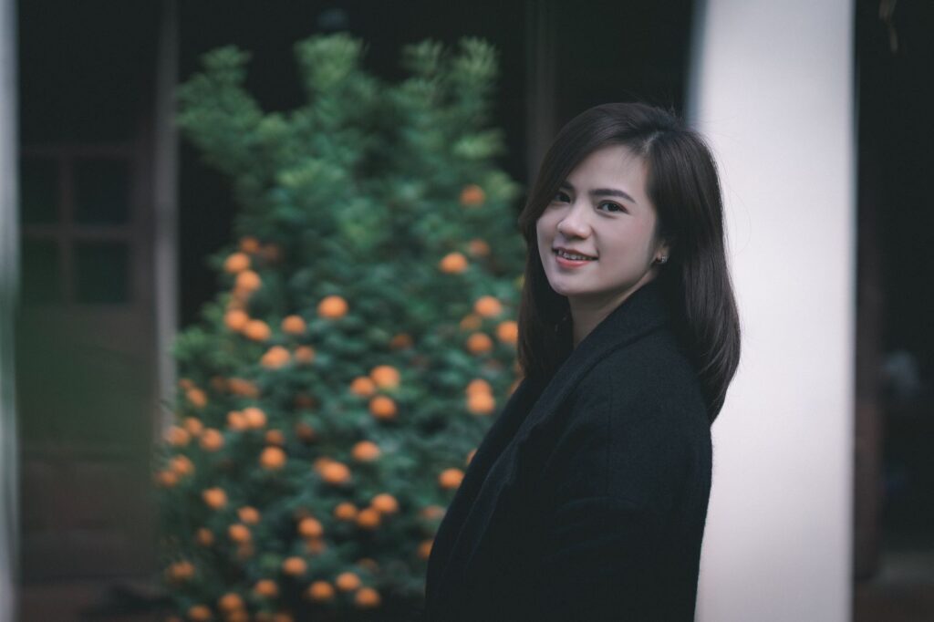 Charming portrait of a smiling woman standing outside near a tree.