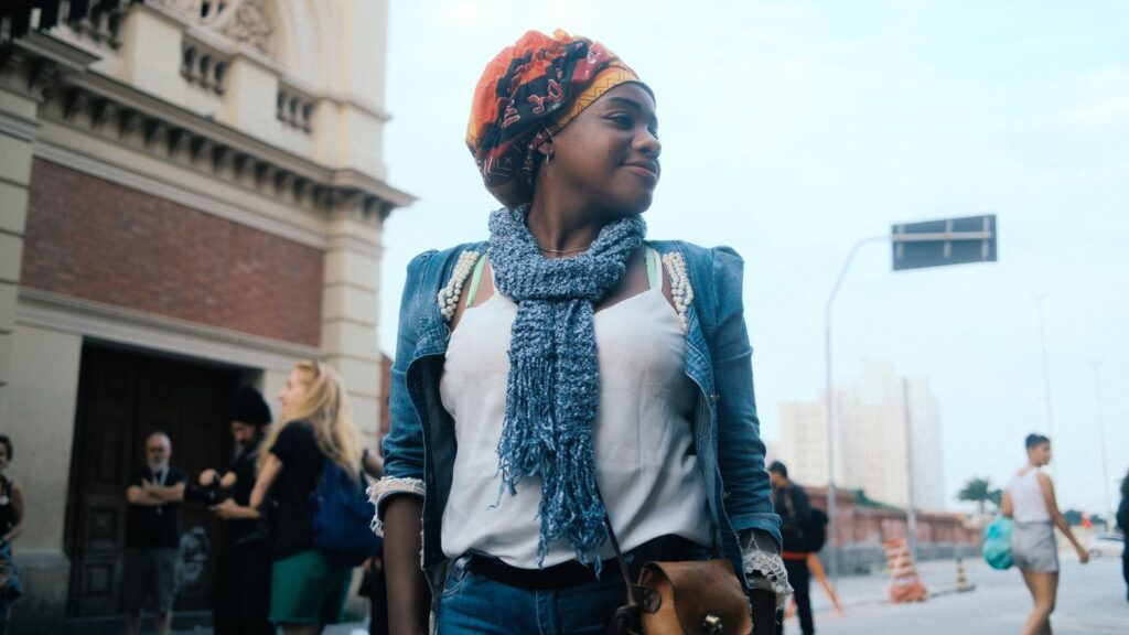 A fashionable young woman stands confidently on a vibrant city street.