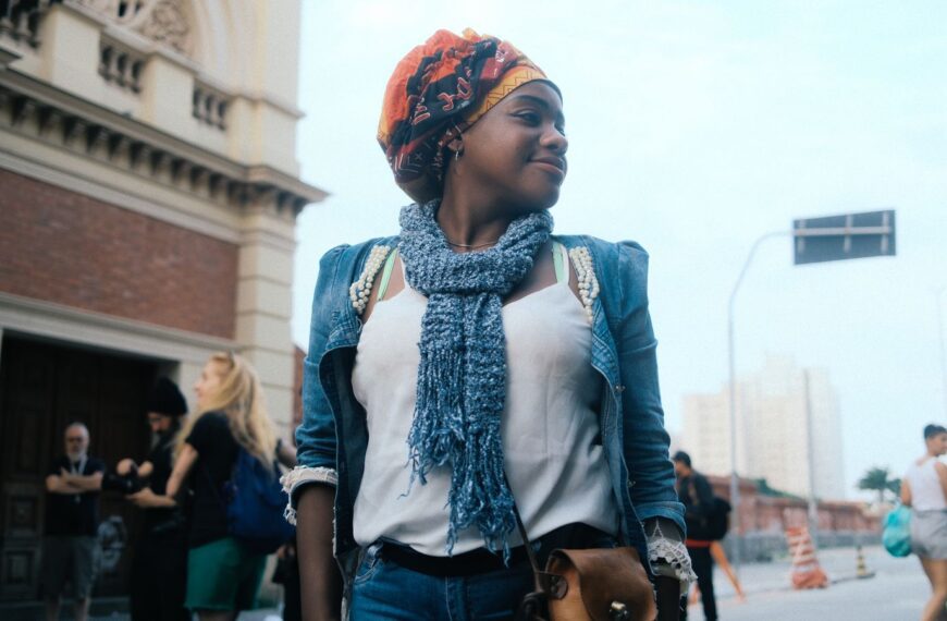 A fashionable young woman stands confidently on a vibrant city street.