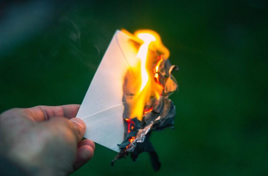 A captivating image of a hand holding a burning paper, symbolizing destruction or release. Perfect for themes of letting go.