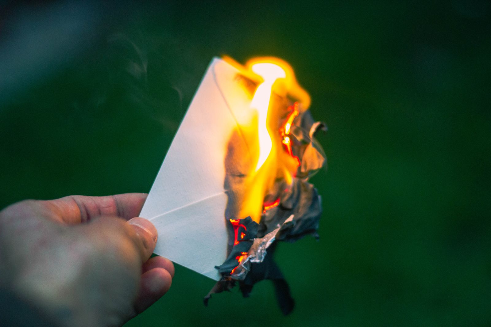 A captivating image of a hand holding a burning paper, symbolizing destruction or release. Perfect for themes of letting go.
