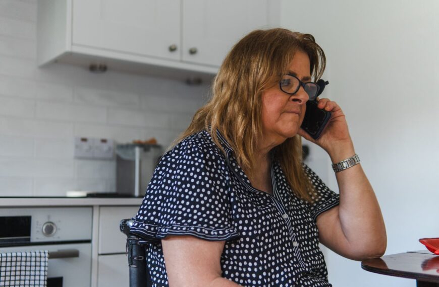 Adult woman talking on phone in a contemporary kitchen, wearing polka dot clothing.