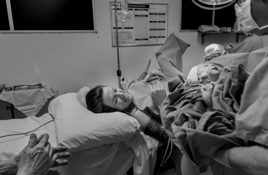 Black and white photo depicting a mother meeting her newborn in the delivery room.