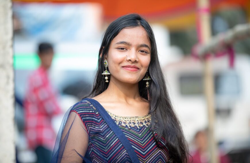 Portrait of a young woman in colorful traditional Indian clothing at an outdoor event.