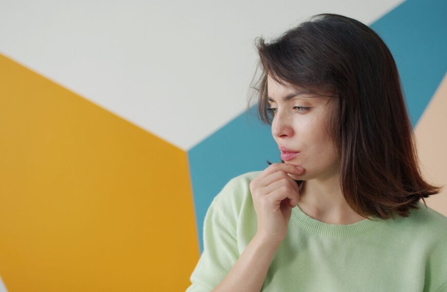 Young woman in contemplation against a colorful geometric background, indoors.