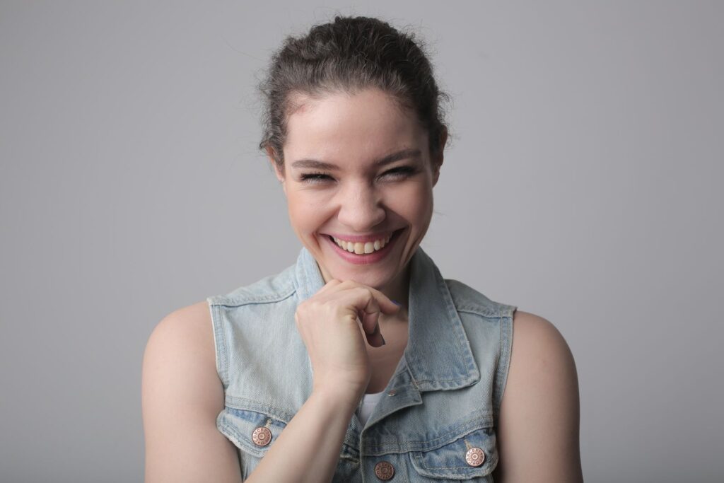 Portrait of a cheerful young woman wearing a denim jacket with a genuine smile.