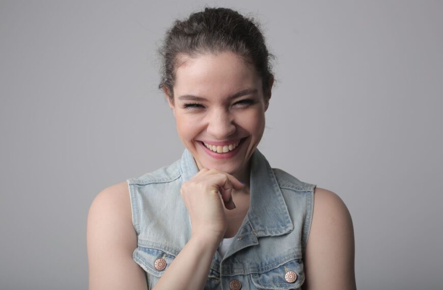 Portrait of a cheerful young woman wearing a denim jacket with a genuine smile.