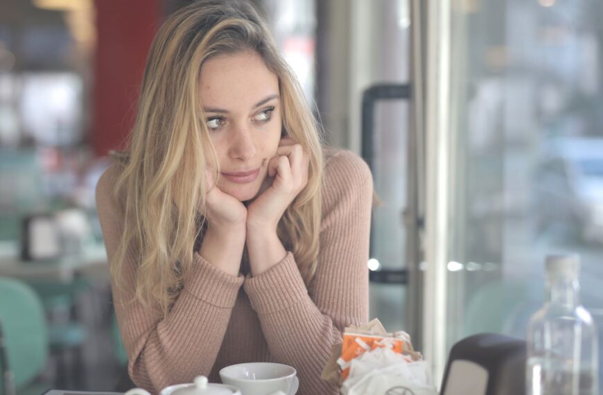 A woman in a cafe looking contemplative with a coffee cup nearby, captured with Canon EOS 5DS.