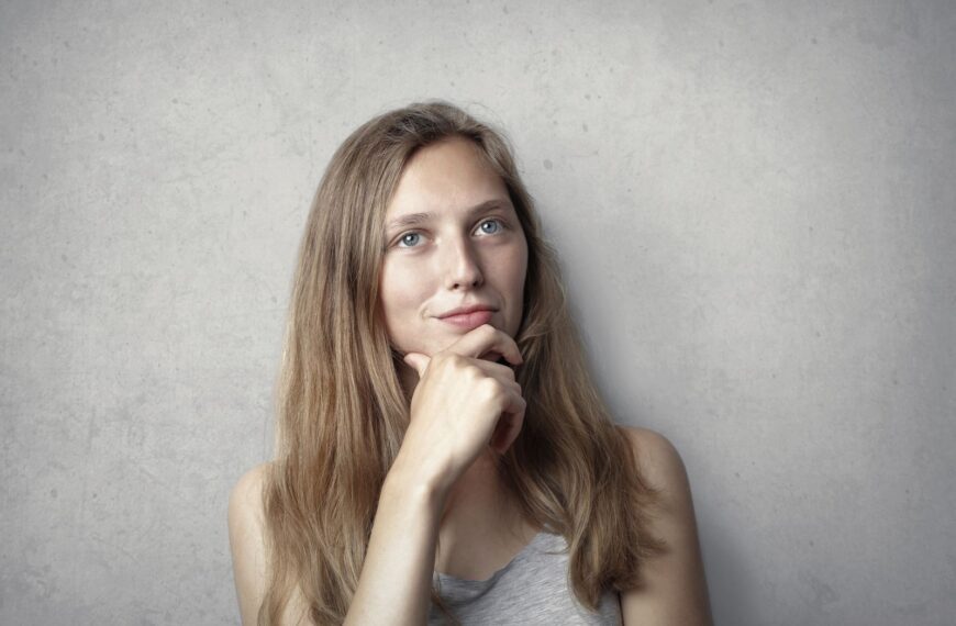 A thoughtful woman contemplates life in a simple portrait with a gray background.