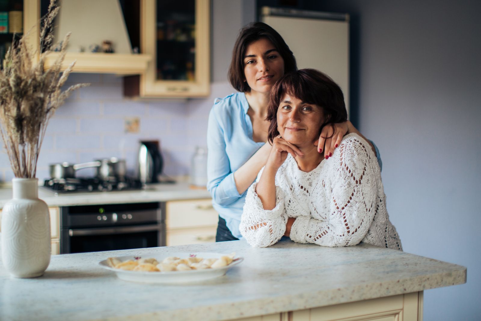 A loving moment shared between mother and daughter in a cozy kitchen, depicting warmth and bonding.