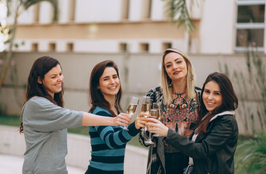 Four women smiling and enjoying a wine toast outdoors, symbolizing friendship and togetherness.
