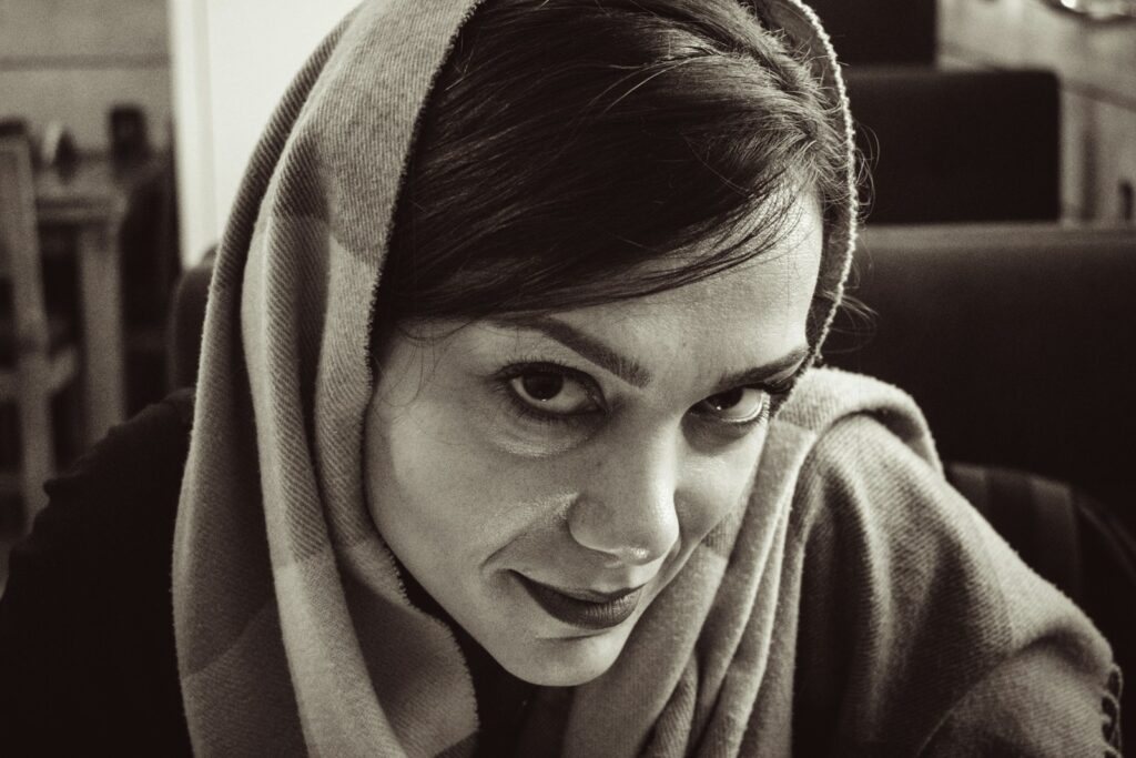 A woman wearing a headscarf looks towards the camera.