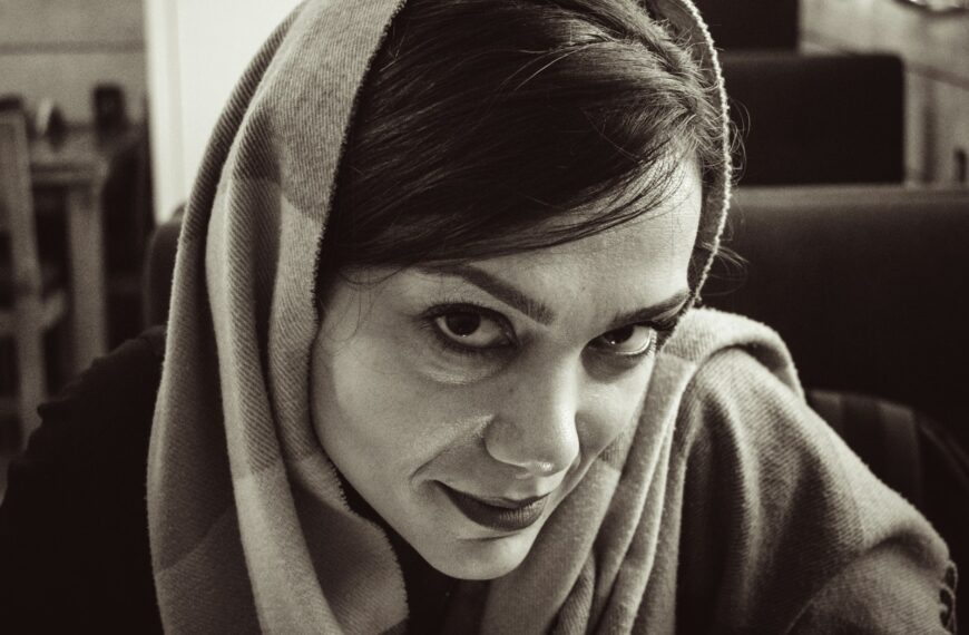 A woman wearing a headscarf looks towards the camera.