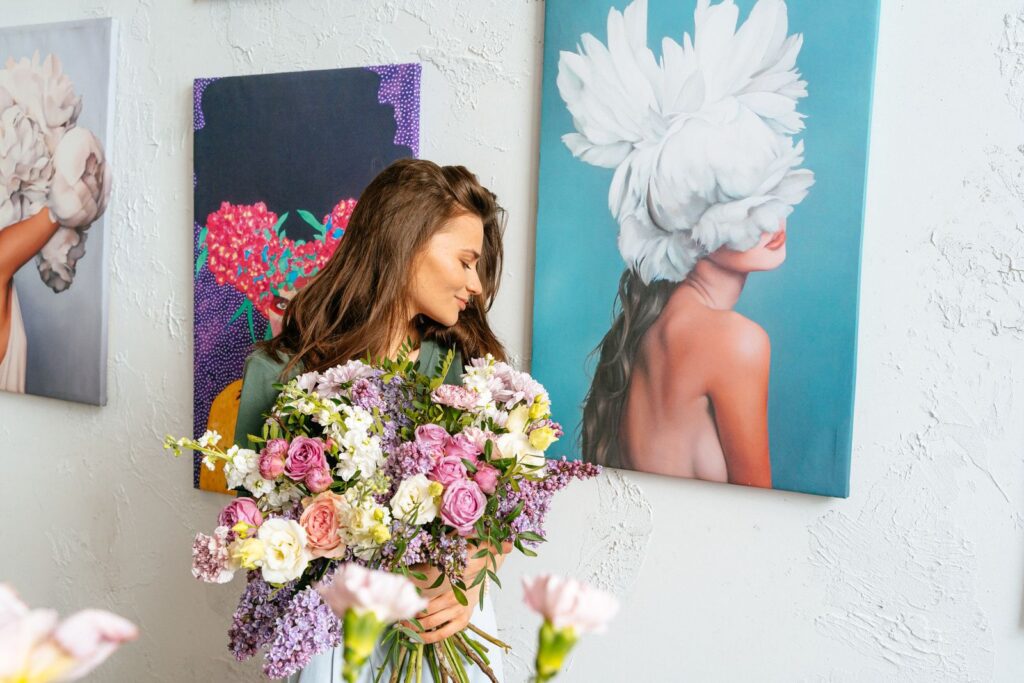 A woman with flowers in front of colorful paintings, blending nature and art.