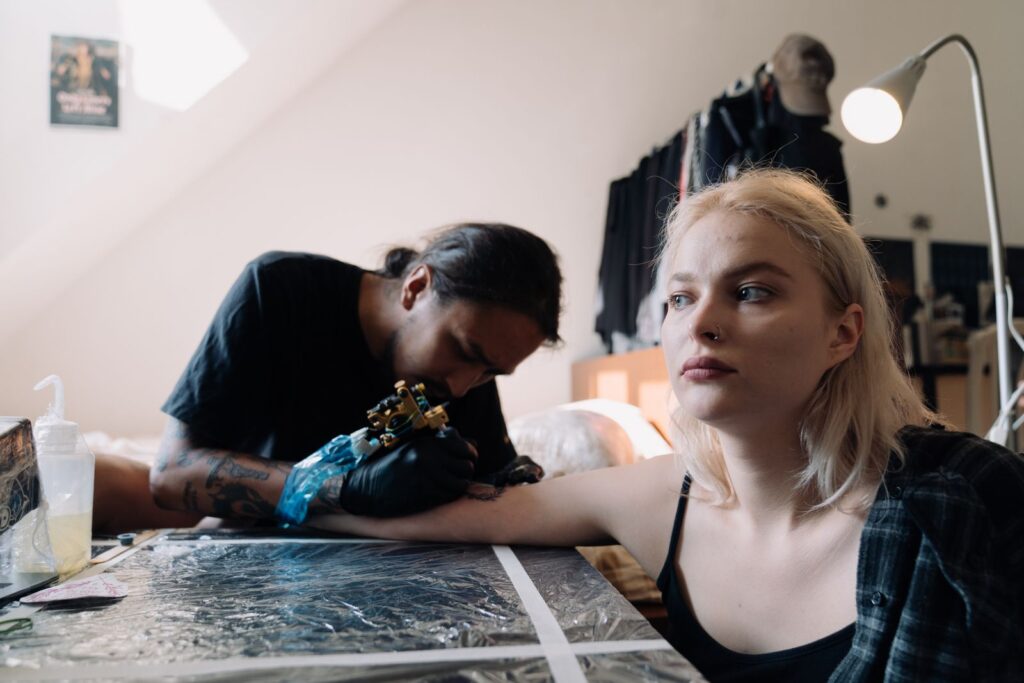 Tattoo artist working on a client's arm in a modern studio environment.