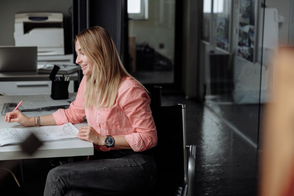 Professional woman sitting at desk working in a bright office setting.