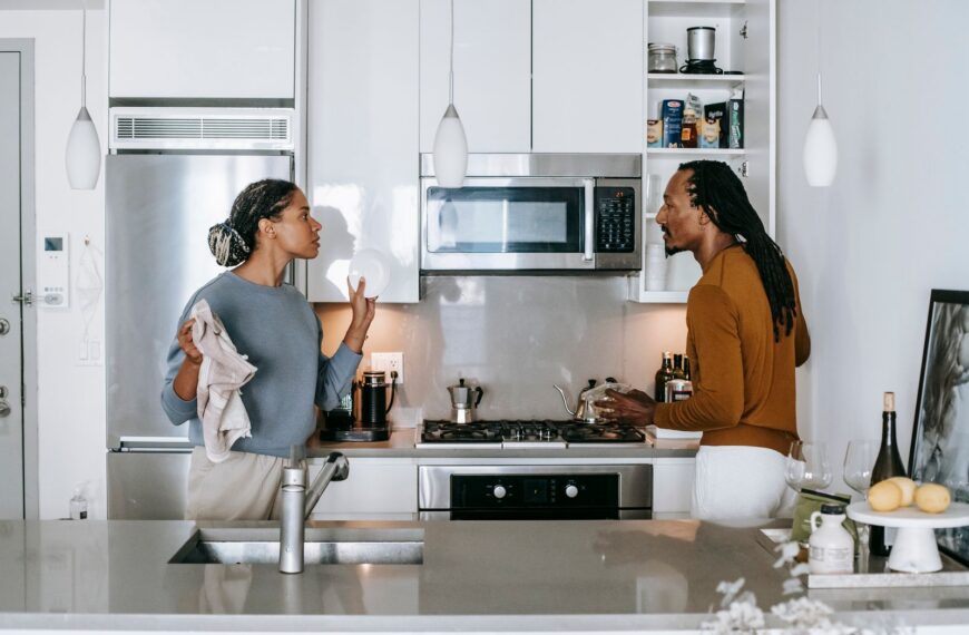 Young black woman talking to annoyed male partner while looking at each other during quarrel in house