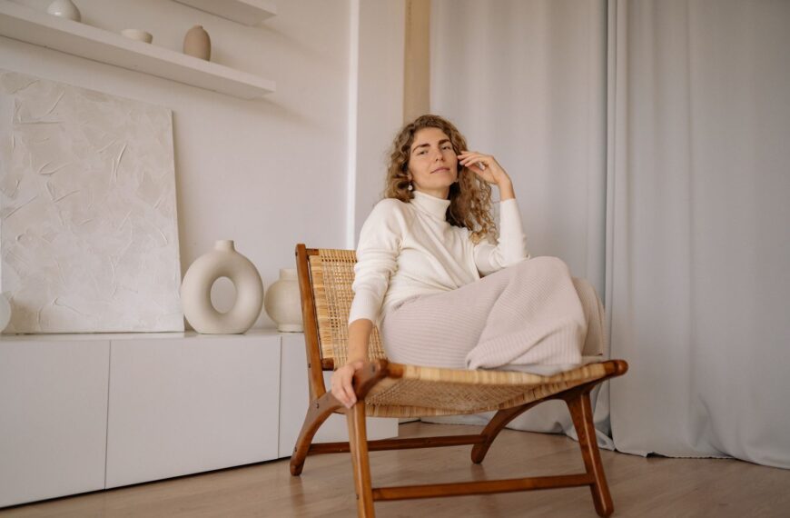 A woman relaxing in a wicker chair indoors with a minimalist background.