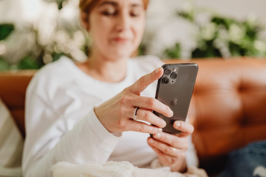 Woman attentively browsing smartphone while relaxing on a comfortable couch indoors.