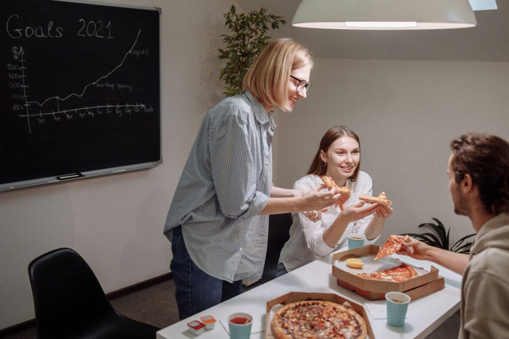 Office team bonding over pizza, discussing goals and strategies to boost productivity.