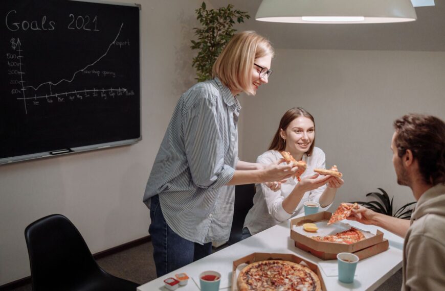 Office team bonding over pizza, discussing goals and strategies to boost productivity.