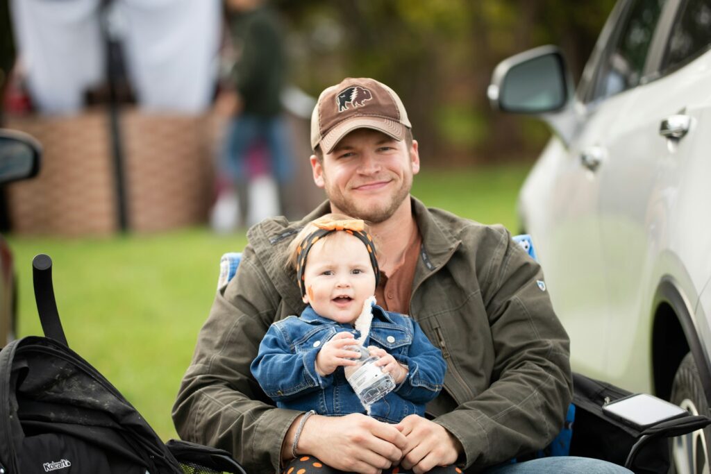 a man holding a baby while sitting in the back of a truck