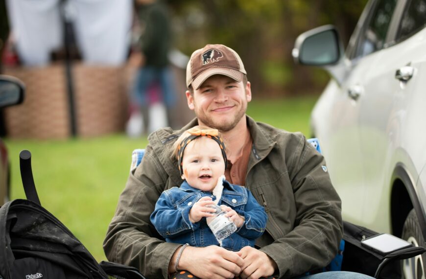 a man holding a baby while sitting in the back of a truck