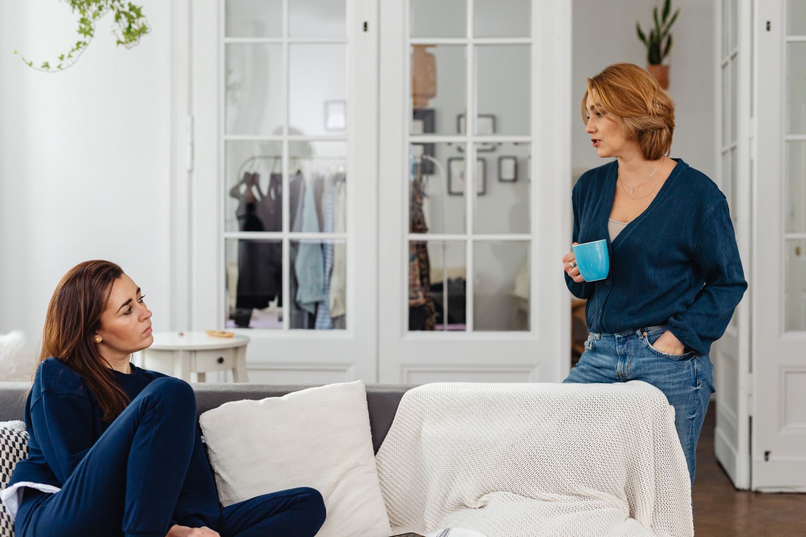 Two women in a cozy home setting having a casual conversation over coffee.
