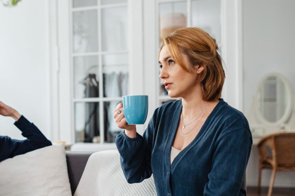 Woman sitting on a sofa holding a mug, enjoying a relaxed moment at home.