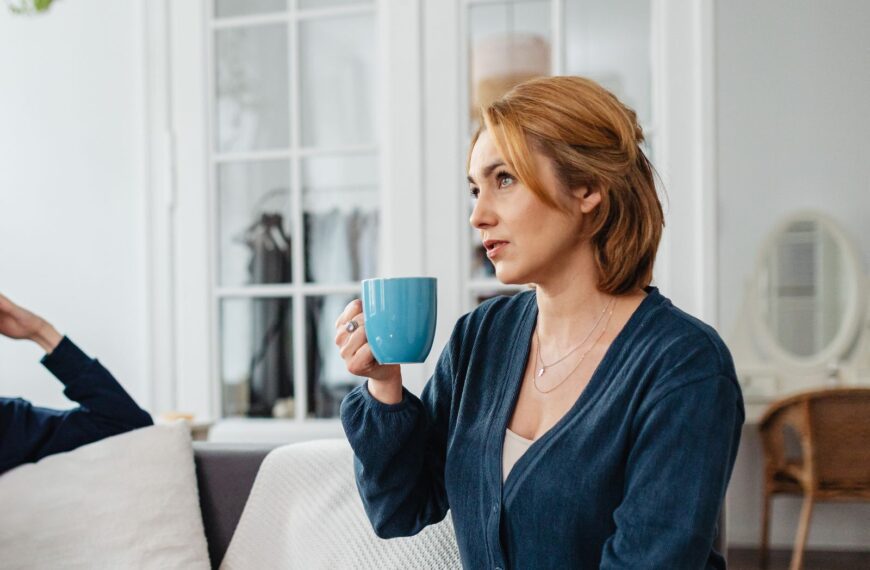 Woman sitting on a sofa holding a mug, enjoying a relaxed moment at home.